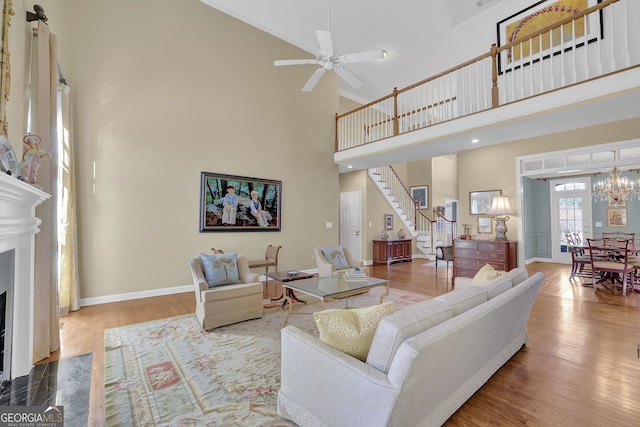 living room with wood-type flooring, a towering ceiling, and a premium fireplace