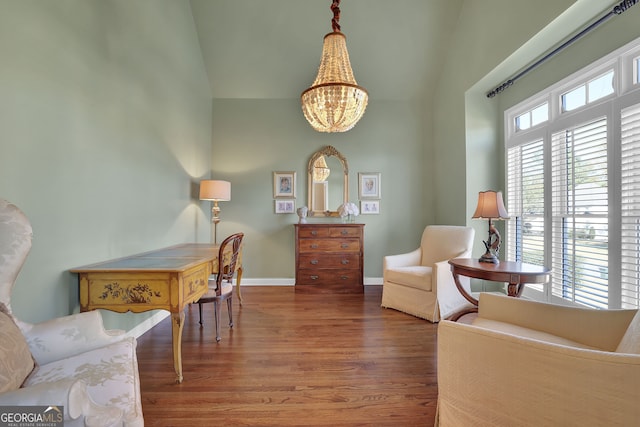 sitting room with dark hardwood / wood-style flooring, vaulted ceiling, and an inviting chandelier