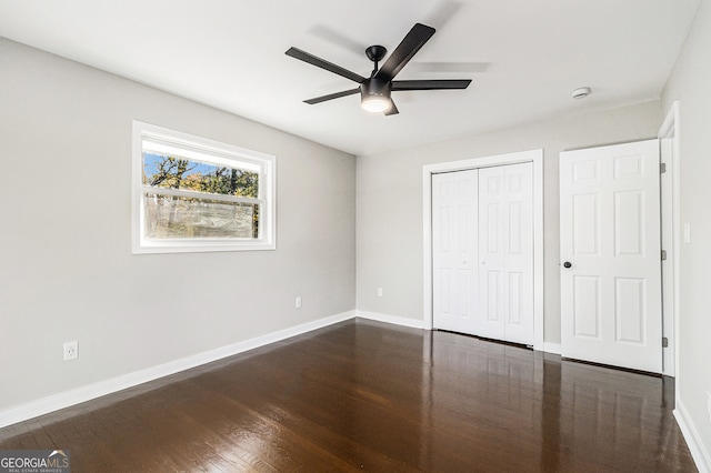 unfurnished bedroom featuring ceiling fan, dark hardwood / wood-style flooring, and a closet