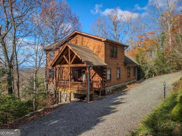 log cabin with driveway, a wooden deck, and roof with shingles