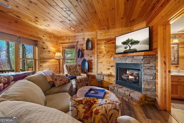 living room featuring wood walls, a stone fireplace, wood-type flooring, and wood ceiling