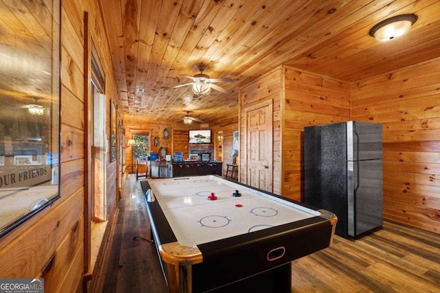 game room with wood-type flooring, ceiling fan, and wooden walls