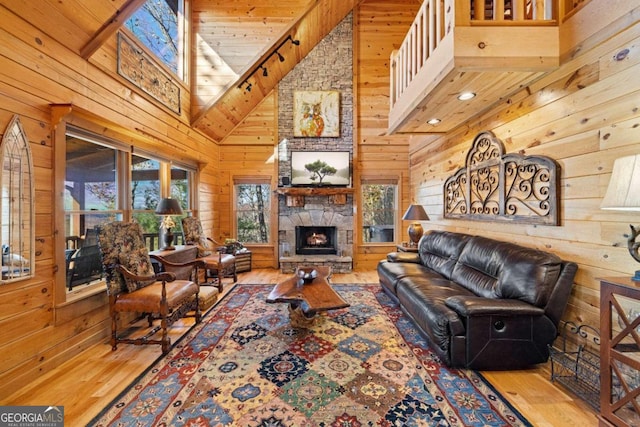 living room featuring hardwood / wood-style flooring, wood walls, a fireplace, and high vaulted ceiling