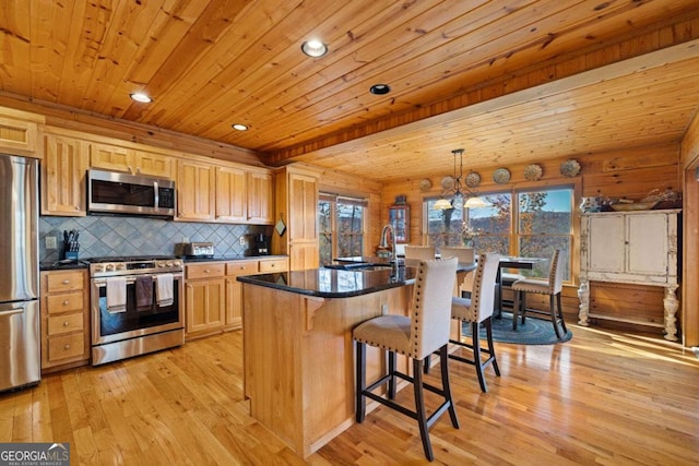 kitchen with a center island, hanging light fixtures, a kitchen breakfast bar, light hardwood / wood-style flooring, and appliances with stainless steel finishes