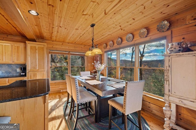 dining area with wood walls, wooden ceiling, and light wood-type flooring