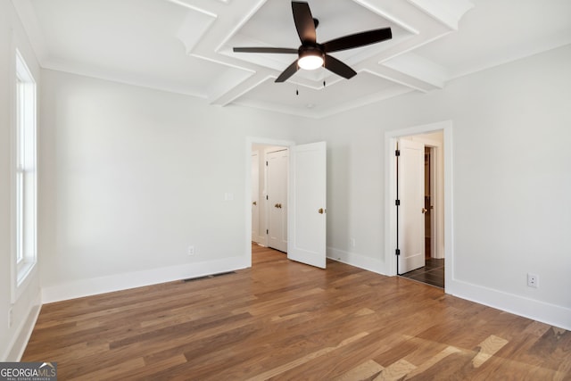 unfurnished bedroom featuring beam ceiling, hardwood / wood-style floors, and multiple windows