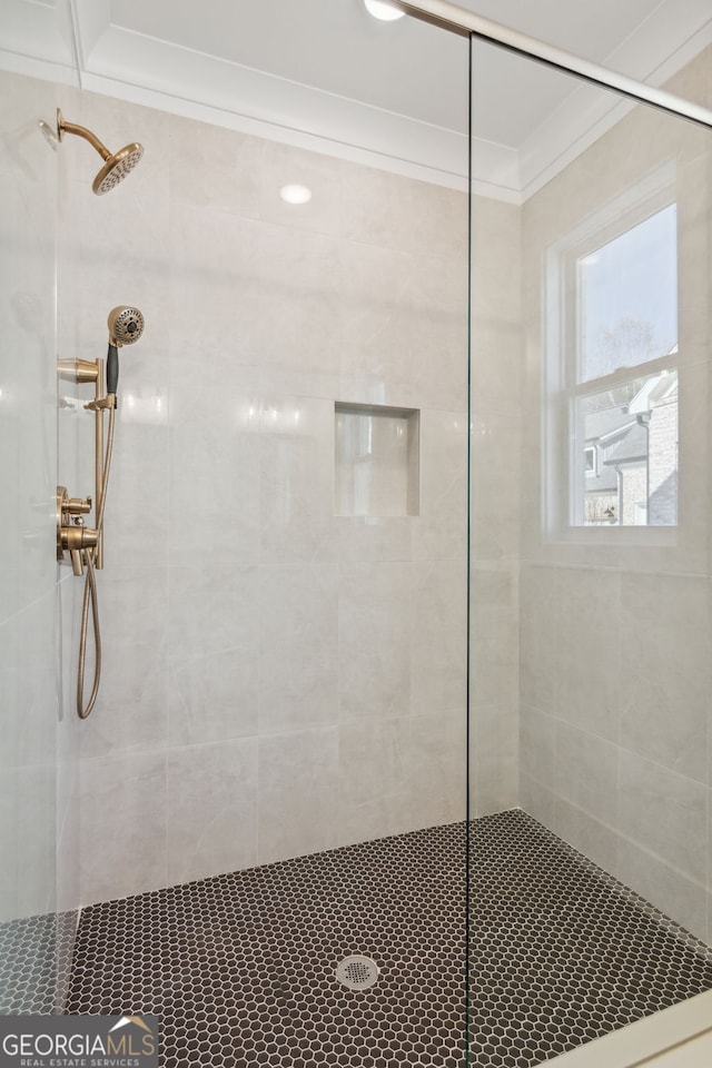 bathroom with a tile shower and ornamental molding