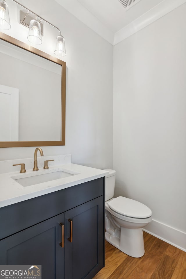 bathroom with vanity, wood-type flooring, ornamental molding, and toilet