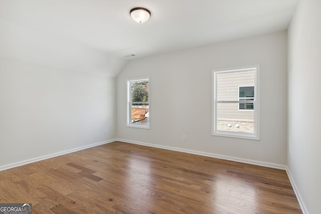 spare room with lofted ceiling and hardwood / wood-style flooring