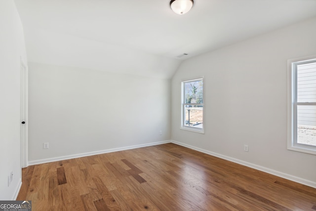 unfurnished room featuring hardwood / wood-style flooring and vaulted ceiling