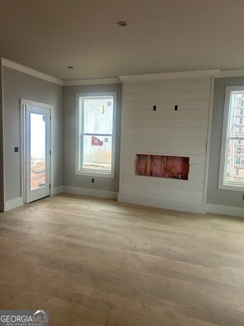 unfurnished living room with crown molding, a fireplace, and light hardwood / wood-style flooring