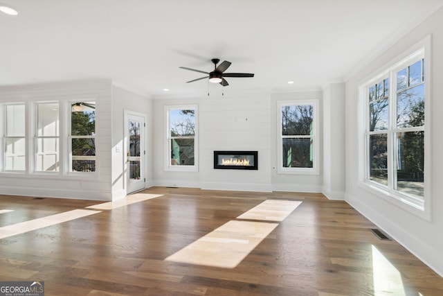 unfurnished living room with ceiling fan, dark wood-type flooring, crown molding, and a fireplace