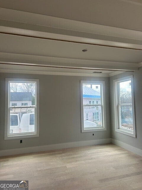 empty room with crown molding and light wood-type flooring