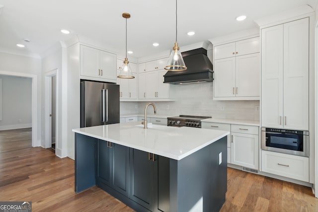 kitchen featuring pendant lighting, sink, high end appliances, white cabinets, and custom exhaust hood