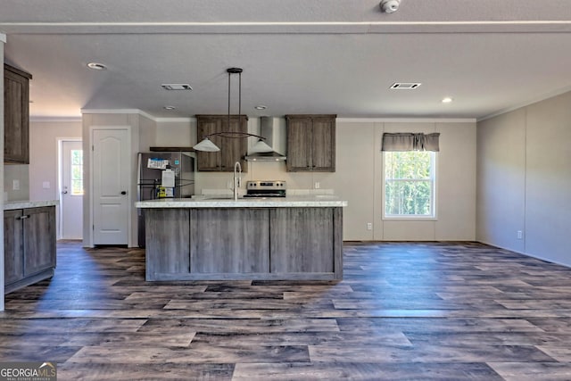 kitchen with appliances with stainless steel finishes, an island with sink, and wall chimney range hood