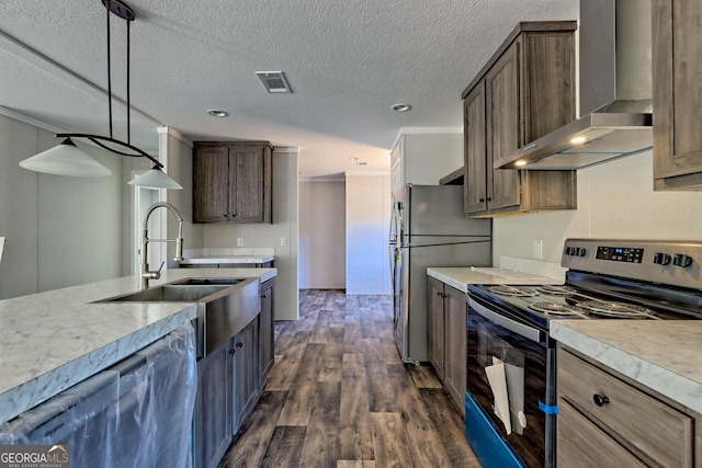 kitchen with wall chimney exhaust hood, sink, decorative light fixtures, appliances with stainless steel finishes, and dark hardwood / wood-style floors