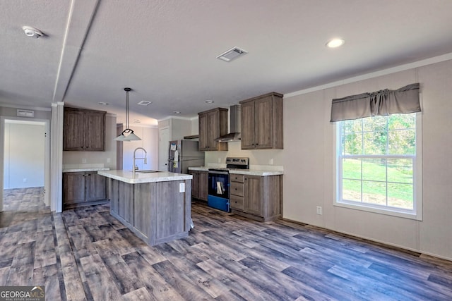 kitchen with wall chimney range hood, sink, appliances with stainless steel finishes, a kitchen island with sink, and decorative light fixtures