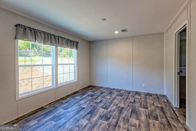 empty room featuring a textured ceiling and dark hardwood / wood-style floors