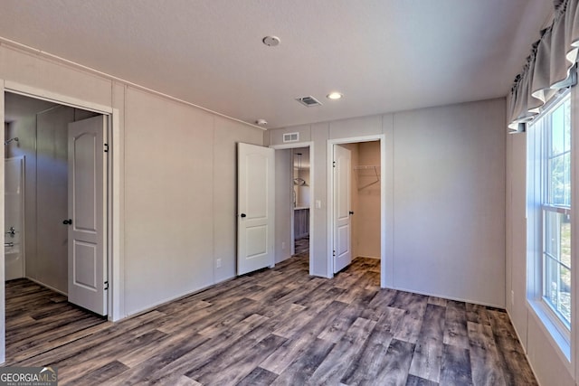 unfurnished bedroom featuring a walk in closet, dark hardwood / wood-style floors, and a closet