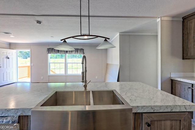 kitchen featuring decorative light fixtures, sink, a kitchen island, and a textured ceiling