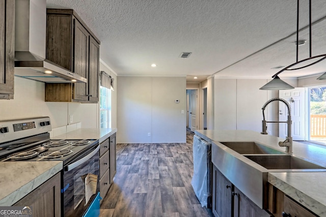 kitchen with wall chimney range hood, sink, hanging light fixtures, stainless steel appliances, and dark hardwood / wood-style flooring