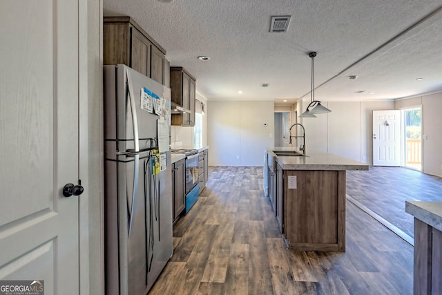 kitchen featuring sink, a kitchen island with sink, stainless steel appliances, dark hardwood / wood-style flooring, and decorative light fixtures