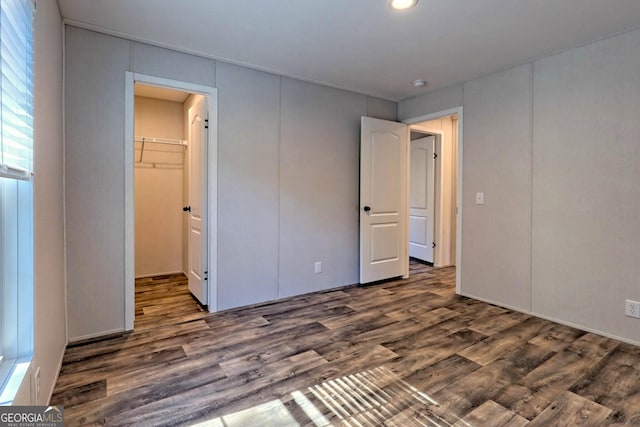 unfurnished bedroom featuring dark hardwood / wood-style flooring, a spacious closet, and a closet