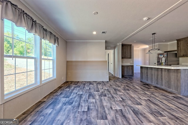 interior space with stainless steel fridge, dark brown cabinetry, crown molding, dark hardwood / wood-style floors, and hanging light fixtures