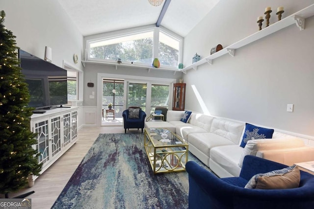 living room featuring beam ceiling, light wood-type flooring, and high vaulted ceiling