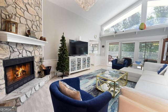 living room with a notable chandelier, light hardwood / wood-style floors, a fireplace, and high vaulted ceiling