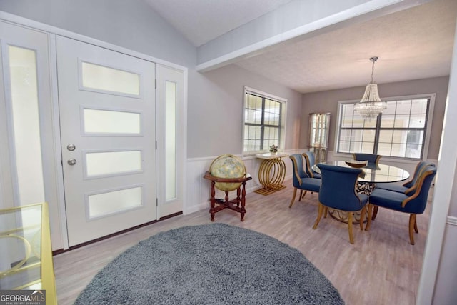 entrance foyer with vaulted ceiling with beams, an inviting chandelier, and light hardwood / wood-style flooring