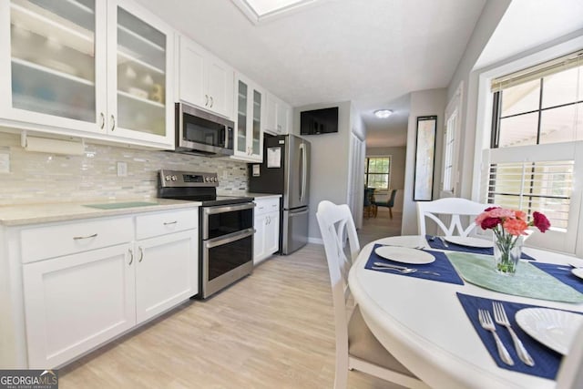 kitchen featuring appliances with stainless steel finishes, white cabinetry, and a healthy amount of sunlight