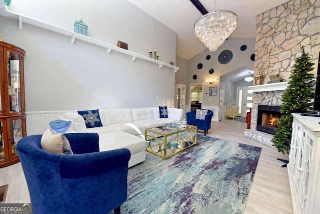 living room with a fireplace, light hardwood / wood-style flooring, high vaulted ceiling, and a notable chandelier