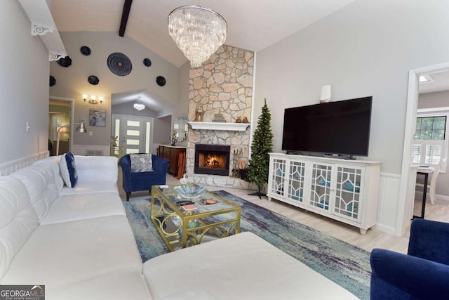 living room featuring a stone fireplace, beamed ceiling, high vaulted ceiling, hardwood / wood-style floors, and a chandelier