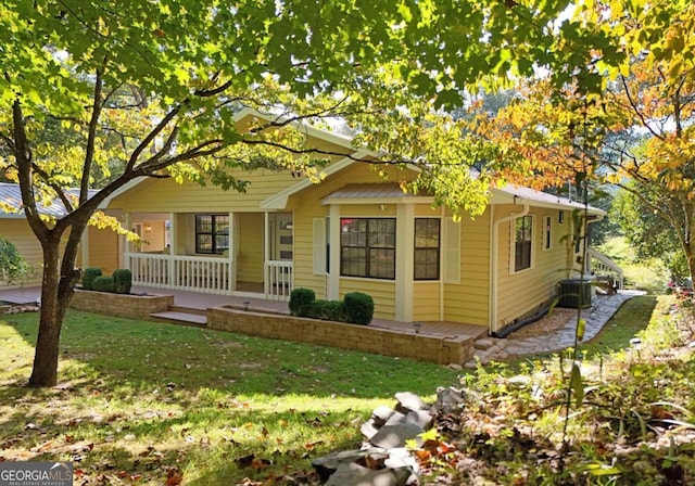 view of front facade featuring central AC, covered porch, and a front yard