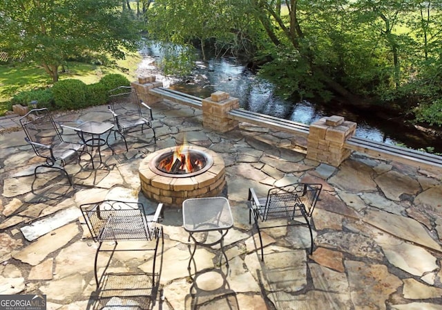 view of patio with a water view and a fire pit