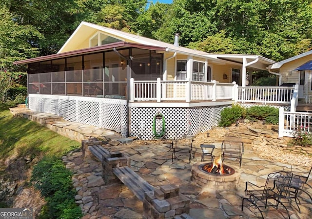 rear view of house featuring a sunroom, a patio area, and an outdoor fire pit