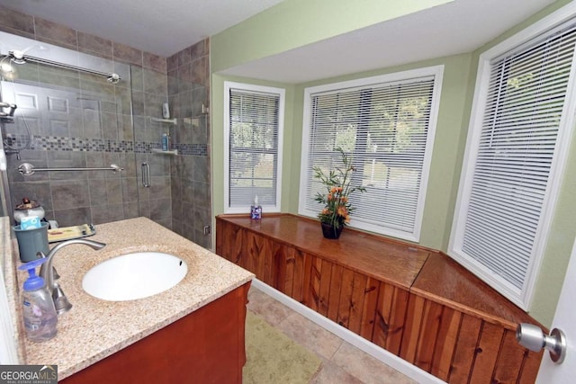 bathroom featuring tile patterned floors, a healthy amount of sunlight, vanity, and a shower with shower door