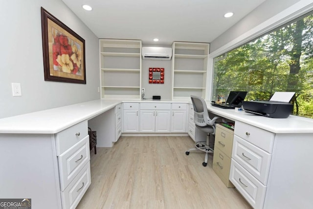 office with light wood-type flooring, built in desk, and a wall mounted AC