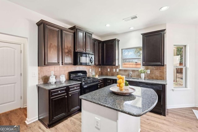 kitchen with black appliances, a center island, light wood-type flooring, and a wealth of natural light