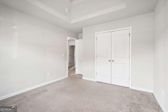 unfurnished bedroom featuring light carpet and a closet