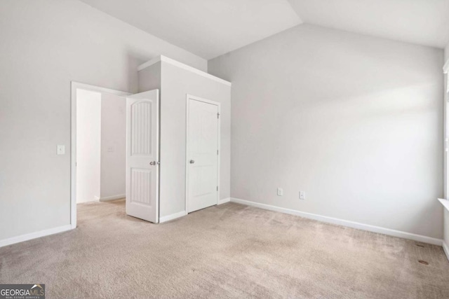 unfurnished bedroom with light colored carpet and vaulted ceiling