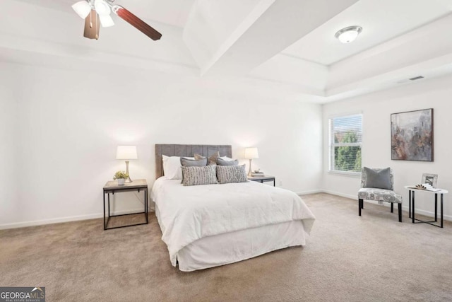 bedroom with light colored carpet, ceiling fan, and a tray ceiling