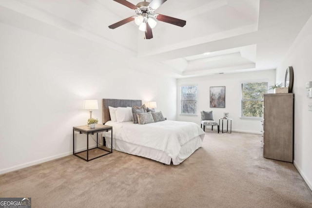 bedroom with a raised ceiling, ceiling fan, and light colored carpet