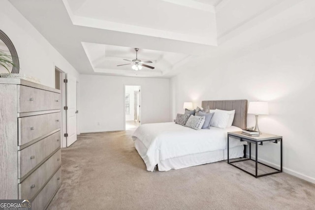 carpeted bedroom with connected bathroom, a raised ceiling, and ceiling fan