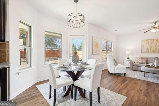 dining room with ceiling fan with notable chandelier and dark hardwood / wood-style flooring