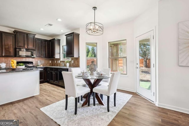 dining space featuring sink, light hardwood / wood-style flooring, and a notable chandelier