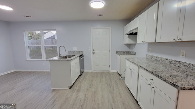 kitchen featuring sink, light stone counters, kitchen peninsula, white cabinets, and light wood-type flooring