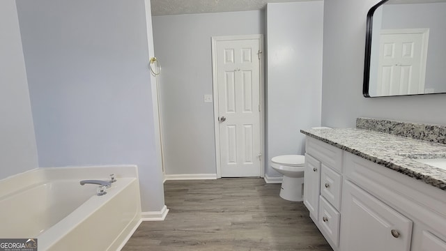 bathroom featuring a bathing tub, hardwood / wood-style floors, a textured ceiling, toilet, and vanity