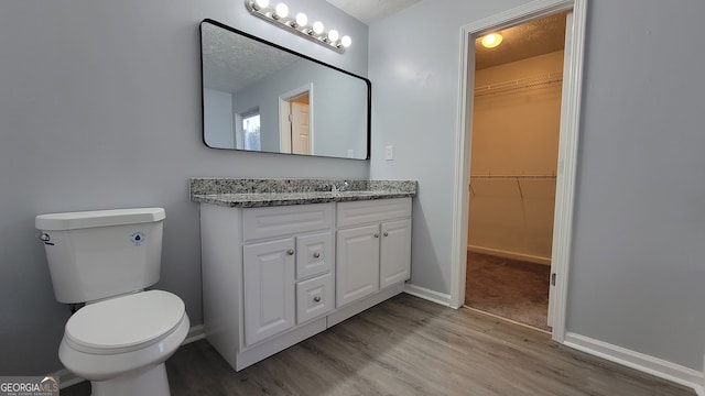 bathroom with a textured ceiling, vanity, hardwood / wood-style flooring, and toilet